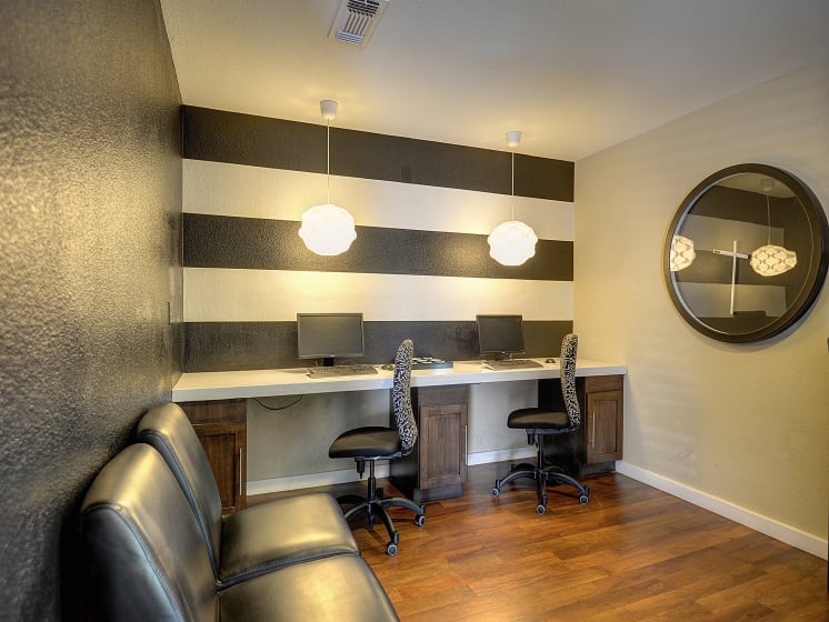 Bussiness Area with Hardwood Inspired Floor, Black/White Patterned Swivel Chairs, Black Sofa, Computers with Keyboard, Round Mirror on Walls and Black/White Walls